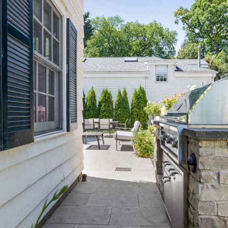 Outdoor Kitchen Adjacent to White Siding and Black Shutters