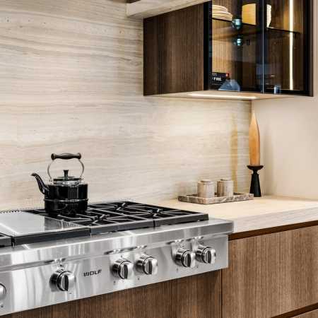 Glass-front illuminated DOCA cabinetry with Neolith stone backsplash, countertops and custom fume hood
