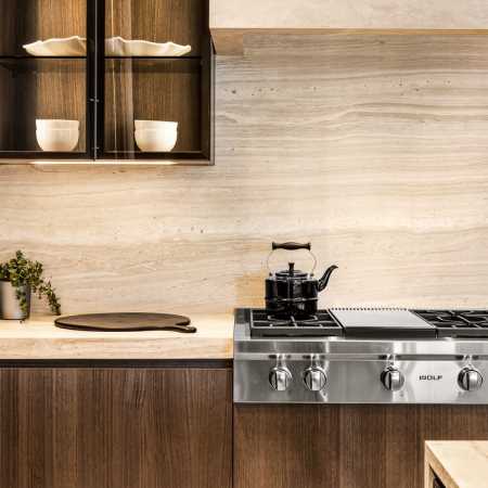 Glass-front illuminated DOCA cabinetry with Neolith stone backsplash, countertops and custom fume hood